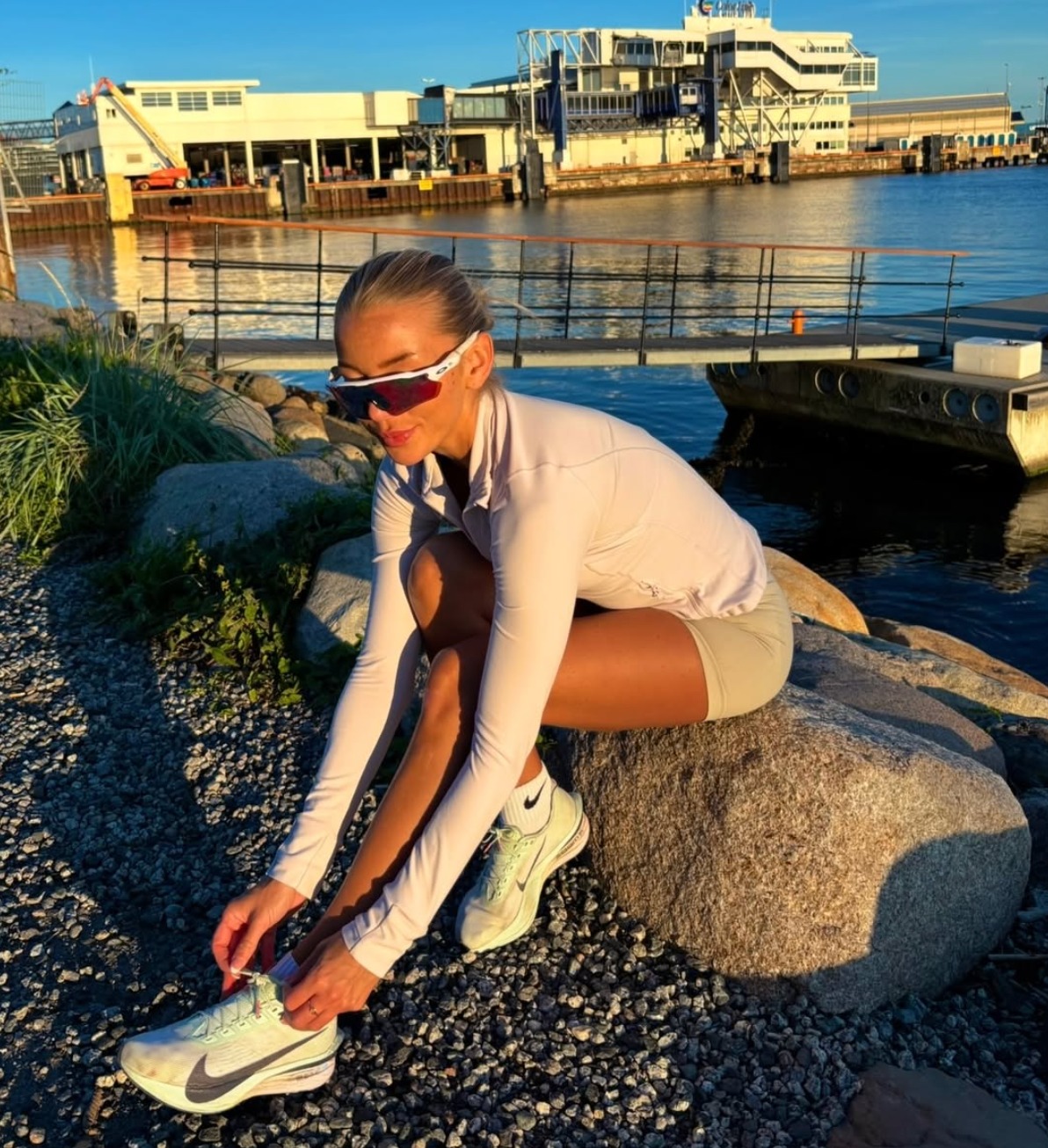 Maren knyter løpeskoene ved vannet før en løpetur.