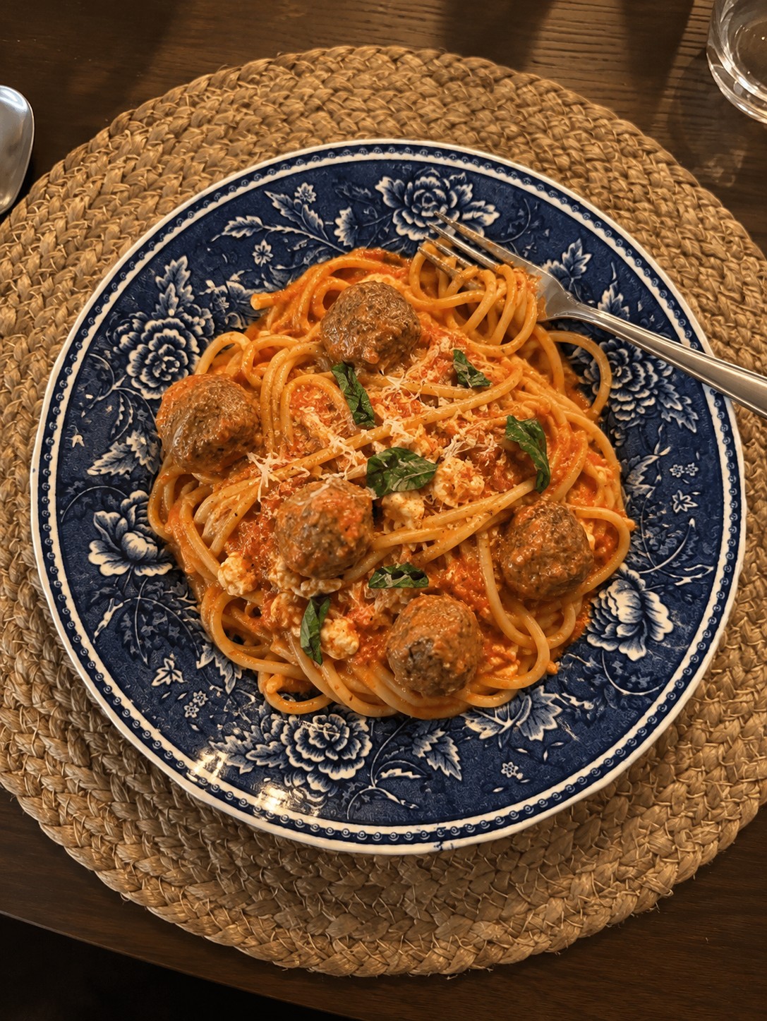 Spaghetti med kjøttboller i tomatsaus på en blåmønstret tallerken.